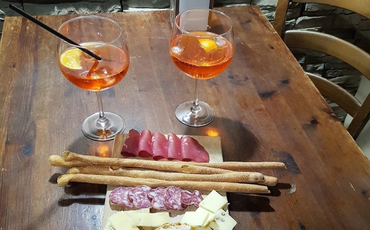 Due spritz e un tagliere di salumi, formaggi e grissini sul tavolo di legno